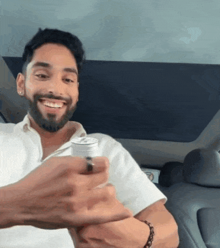 a man with a beard is smiling and holding a can