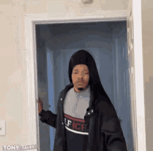 a man is standing in a doorway wearing a hooded jacket .