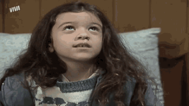 a young girl with long hair looks up at the sky with viva written on the bottom of the screen