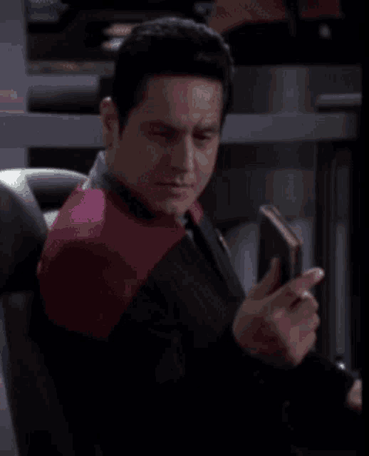a man in a red and black jacket is looking at his phone