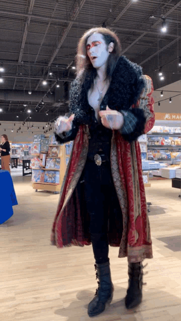 a man in a red and black coat is standing in a store with a sign that says mac