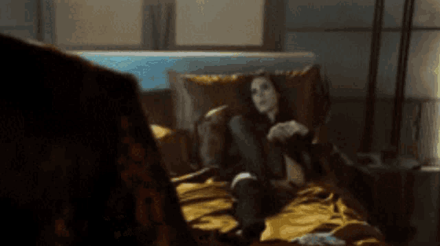 a woman is laying on a bed in a dark room with a lamp in the background .