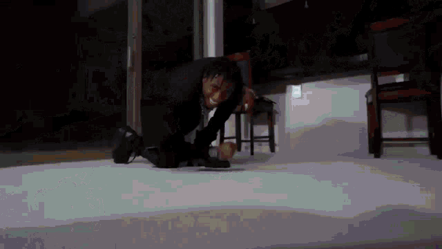 a man in a suit is kneeling on the floor in a dark room