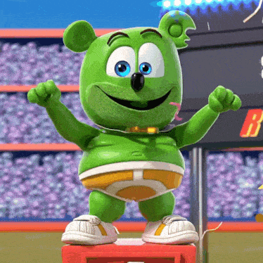 a green gummy bear with blue eyes is standing on a podium with the letter b in the background