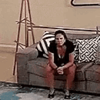 a woman is sitting on a couch in a living room with a lamp .