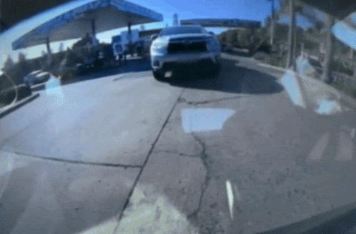 a car is parked in front of a gas station with a sign that says ' chevron ' on it