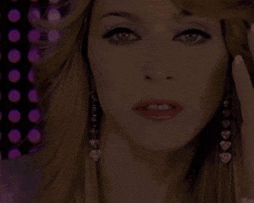 a close up of a woman 's face wearing earrings with hearts on them