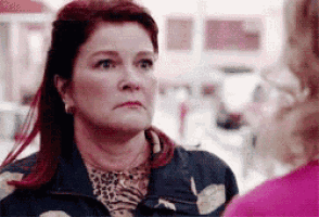 a woman with red hair is talking to another woman while wearing a leopard print shirt .