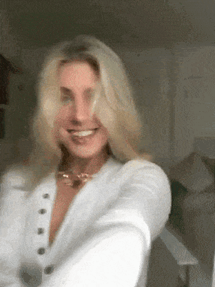 a woman is wearing a white shirt and a gold necklace .