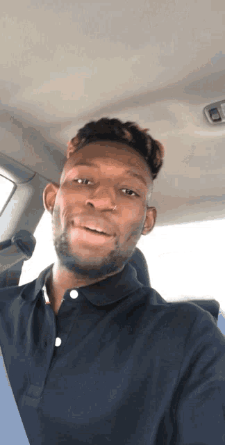 a man in a black shirt is smiling while sitting in the back seat of a car