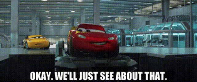 a red car is sitting on a conveyor belt next to a yellow car in a garage .