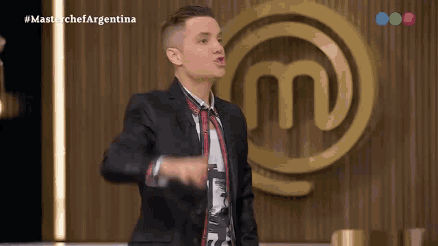 a man in a suit and tie stands in front of a masterchef argentina logo