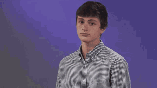a man in a plaid shirt holds a tennis racquet