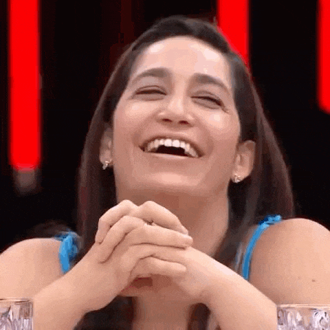 a woman is laughing with her eyes closed and her hands folded in front of her face .