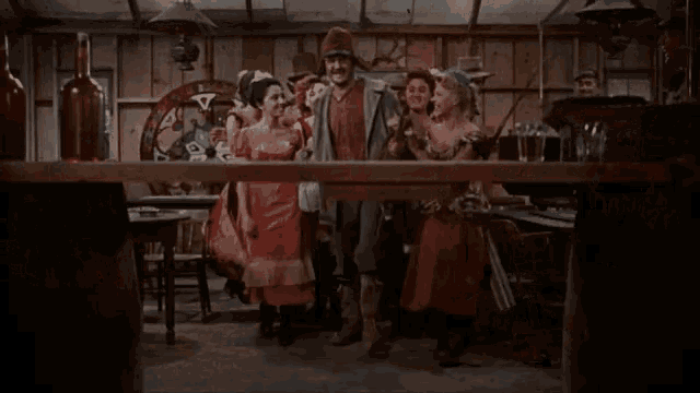 a group of people are standing around a wooden table in a room .