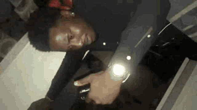 a man in a black shirt is laying on a table holding a flashlight .