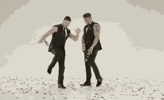 two men in suits are holding roses in their hands and dancing