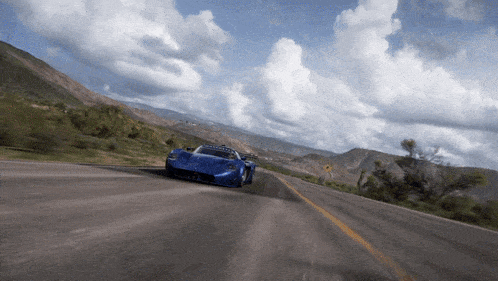 a blue car is driving down a mountain road