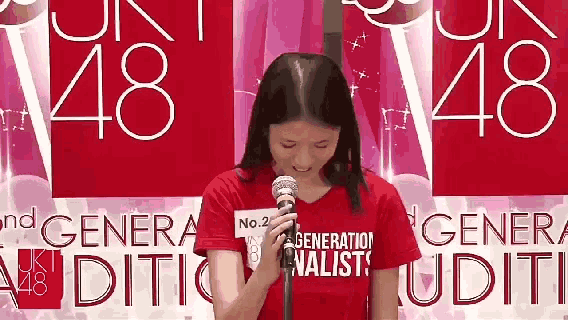 a woman is holding a microphone in front of a sign that says generation finalists