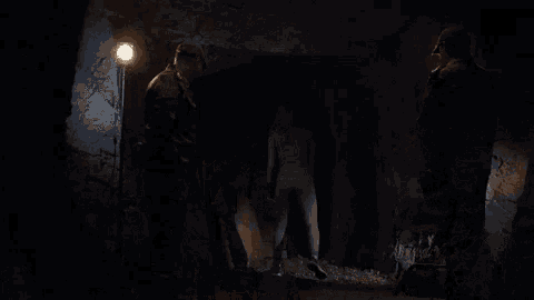 a woman stands in front of a group of soldiers in a dark room