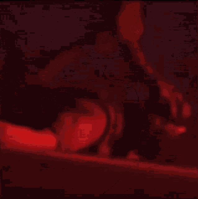 a person is dancing in a dark room with red lights behind them