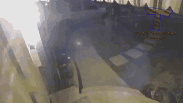 a blurred image of a person walking down stairs with a blue t on the bottom right