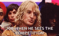 a man with blonde hair is standing in front of a crowd of people .