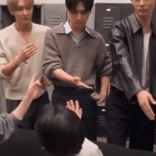 a group of young men are standing next to each other in a room with lockers .