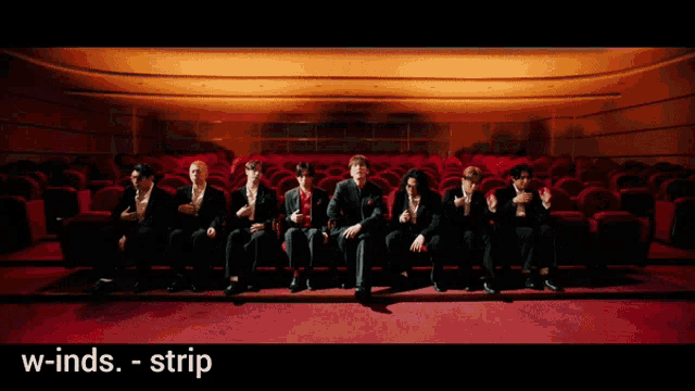 a group of men are sitting in an auditorium with the words w-inds strip on the bottom right
