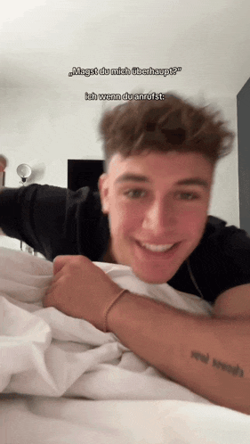 a young man laying on a bed with a tattoo on his arm