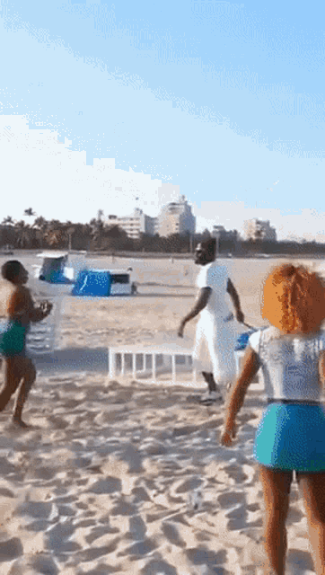 a group of people are running on a beach and one of them is wearing a shirt that says ' miami ' on it