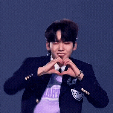 a young man in a suit and tie is making a heart with his hands .