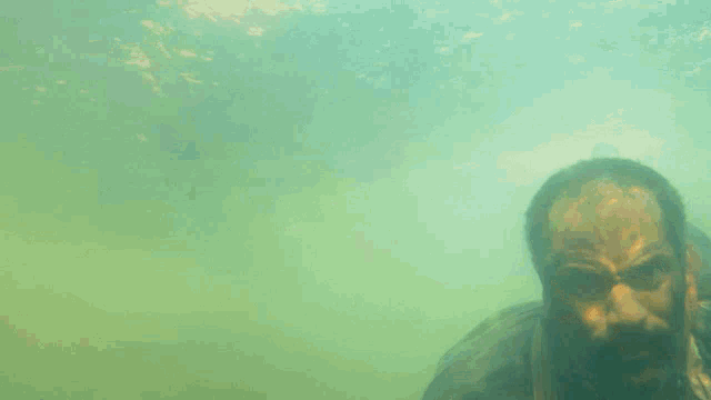 a man with a beard is swimming in a body of water