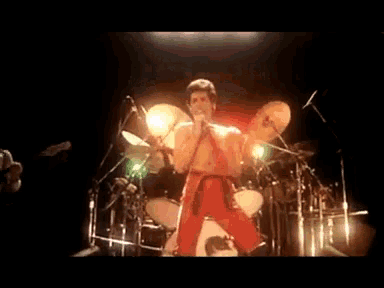 a man in red pants is singing into a microphone on stage .