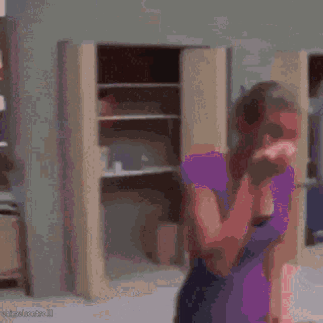 a woman in a purple dress is covering her face while a man in a white shirt stands in front of a closet