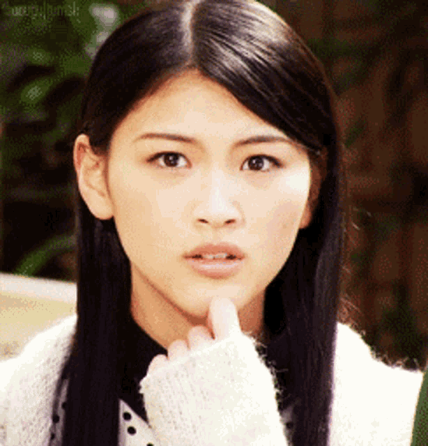 a woman with long black hair is wearing a white sweater and black shirt