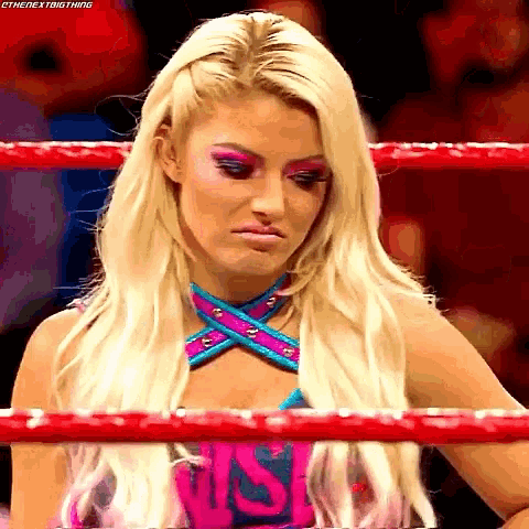 a woman is standing in a wrestling ring and making a sad face .