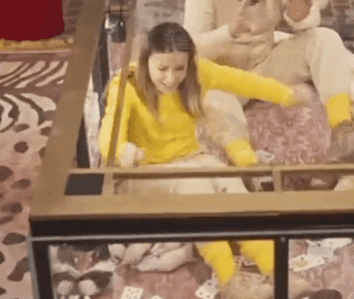 a woman in a yellow sweater and yellow socks is sitting on the floor playing a game of cards .