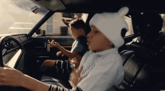 a boy wearing a white hat with ears is driving a car