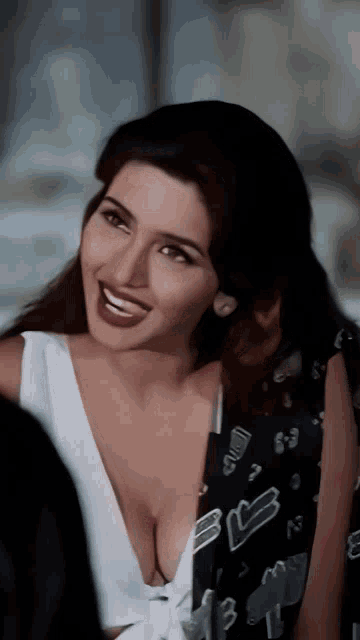 a woman with a plunging neckline is smiling and wearing a black jacket with the letter b on it