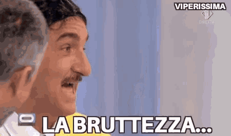 a man with a mustache says la bruttezza while standing next to another man