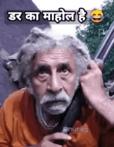 a man with a beard is holding a gun in his hand .