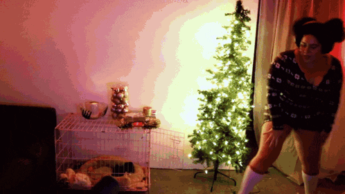 a woman is standing in front of a small christmas tree