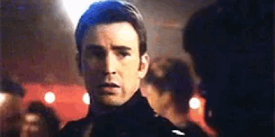 a man in a black jacket and tie is standing in a crowd of people .