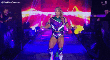 a woman in a purple and green outfit is walking down a blue aisle .