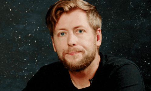 a man with a beard wearing a black shirt is smiling