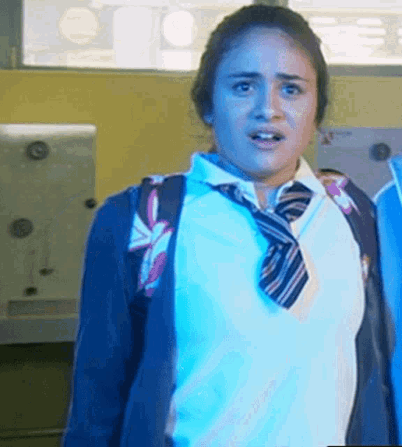 a girl wearing a tie and a white shirt is standing in a room