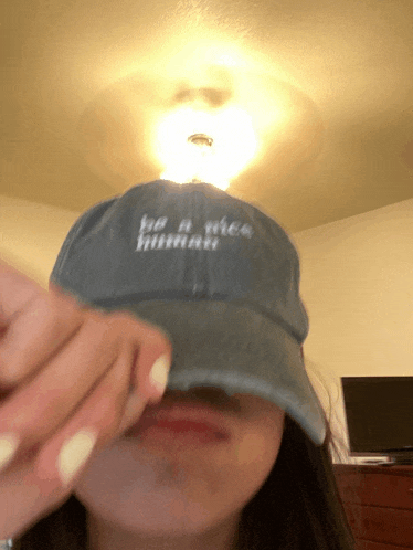 a woman wearing a blue hat that says be a nice human