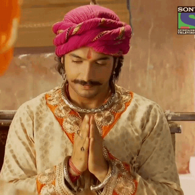 a man wearing a pink turban is praying in front of a sony logo