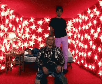a man in a black shirt is standing next to a woman in purple pants in a room with red stars on the wall